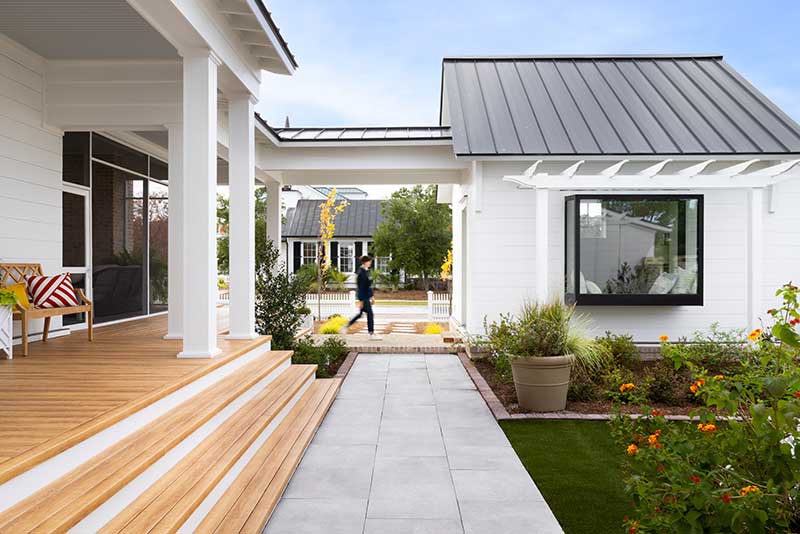 A woman walking to the guest house of the Southern Living Idea House in North Carolina, featuring Marvin Ultimate and Marvin Elevate windows and doors as well as Marvin Skycove.