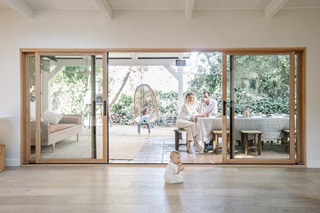 A photo through a Marvin multi-slide patio door of Amber Lestrange and her family sitting in their outdoor space.