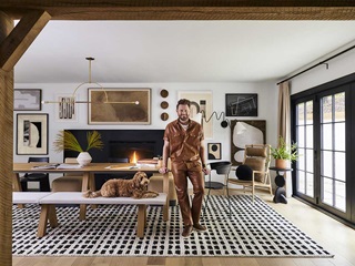 Bobby Berk and his dog in the dining room of the Bobby Berk Firm’s office, featuring a Marvin Ultimate Bi-Fold Door.