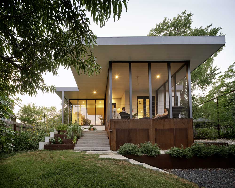 Two people and a dog on the back porch of a passive home in Austin, TX, featuring Marvin  Elevate Direct Glaze windows.