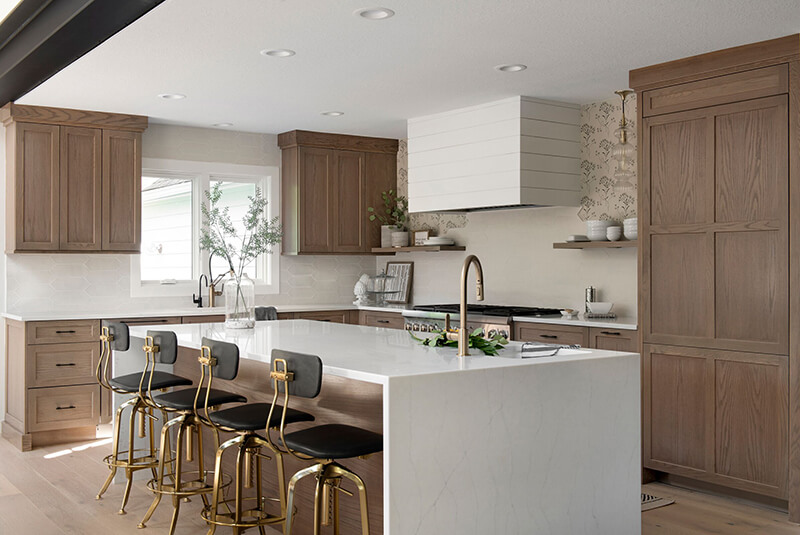 Katie Kurtz’s redesigned kitchen with a large white center island and medium oak cabinets.