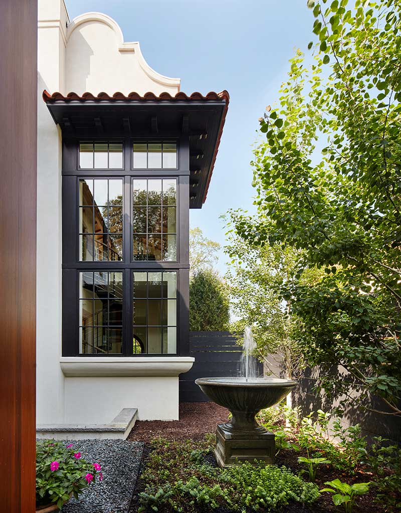 A close up of the exterior of a Modern Mediterranean style home featuring Marvin Elevate Casement Picture windows and a water fountain.