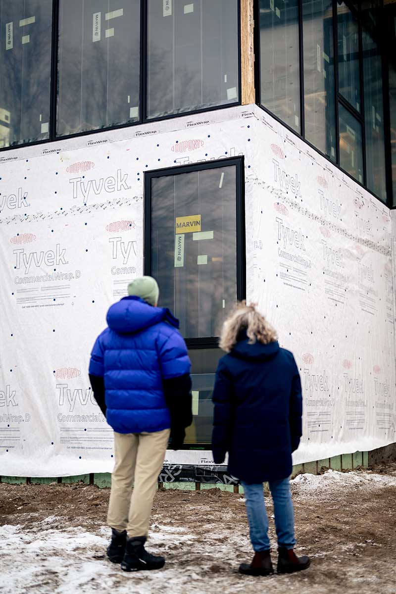 A man and a woman looking at a Marvin Modern window on an under construction home.