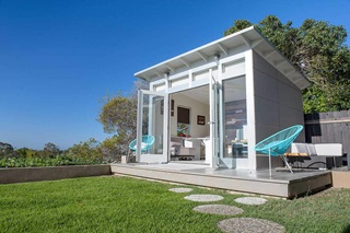 A modern, prefab Studio Shed complete with artwork, windows and furniture.