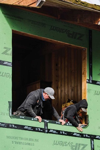 Two men prepping a window opening with flashing tape from inside the home.